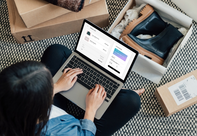 Woman sitting cross-legged with her laptop surrounded by online shopping packages