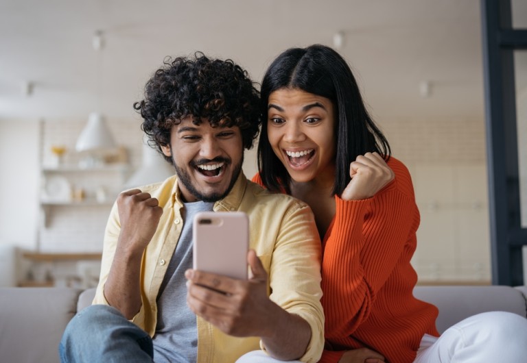 Couple looking at a phone with big smiles on their faces